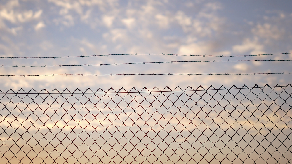 Fence,With,Barbed,Wire,Against,Sunset