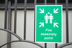 Fire,Assembly,Point,Sign,At,Workplace,Car,Park,Fence