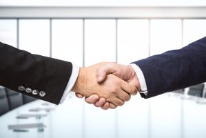 Handshake,Of,Two,Businessmen,On,The,Background,Of,Bright,Conference