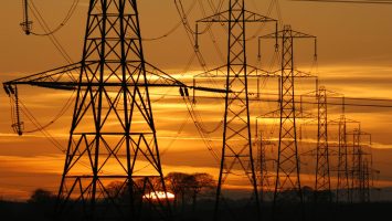 Sun,Setting,Behind,A,Row,Of,Electricity,Pylons